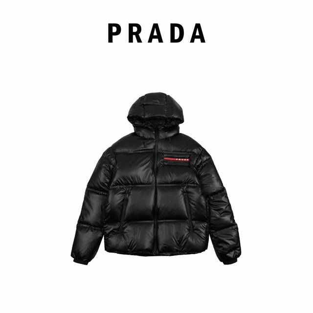 Prada 普拉达 21Fw 红条标识羽绒服 此款廓形丰满的羽绒外套采用linea Rossa独特的双层轻质粘合尼龙面料打造，搭配连帽衣领、直裁衣袖和正面拉链拉